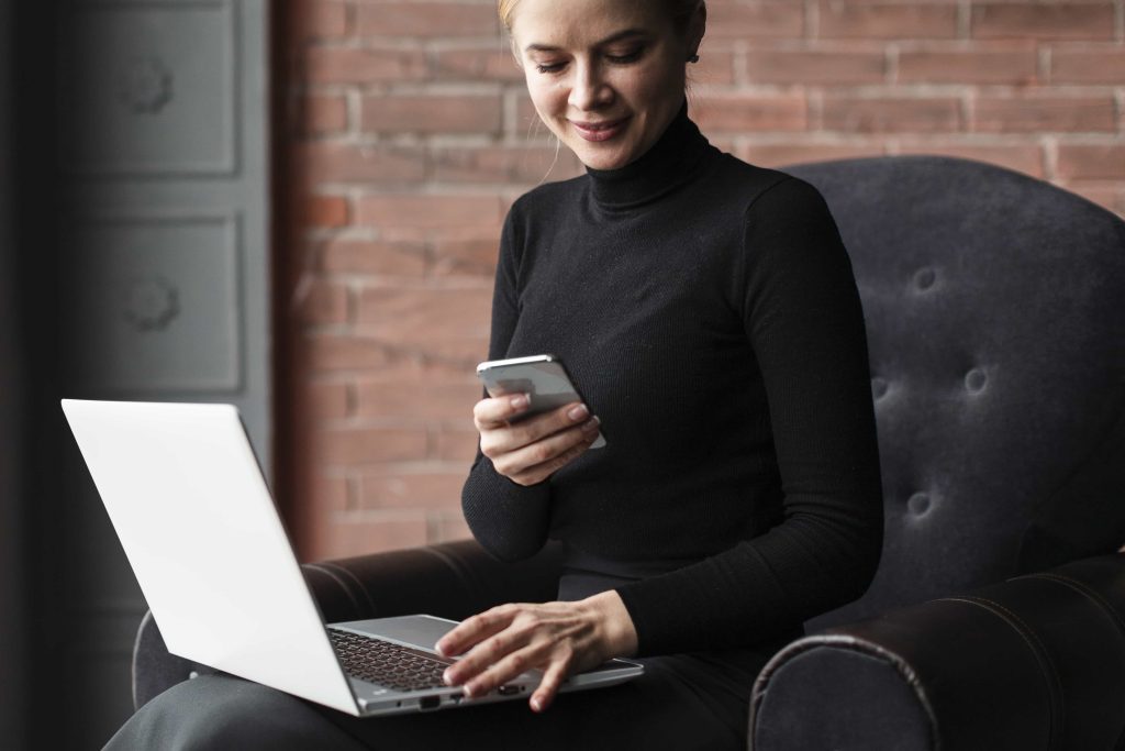 Person browsing at phone and laptop